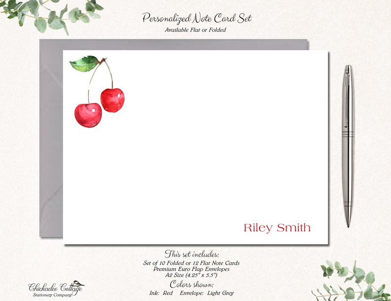 May include: A set of personalized note cards with a watercolor illustration of two red cherries. The cards are available in folded or flat styles and come with envelopes. The text on the card reads "Riley Smith".