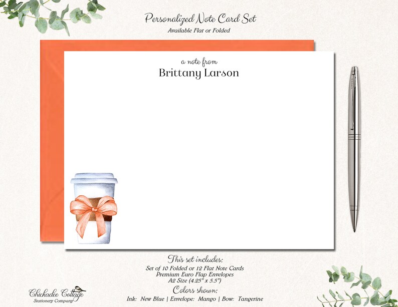 May include: Personalized note card set featuring a watercolour illustration of a coffee cup with a pink ribbon. The set includes 10 folded or 12 flat note cards and envelopes. The card size is 10.8 cm by 14 cm. The ink colour is new blue, the envelope colour is mango, and the bow colour is tangerine.