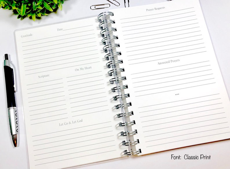 May include: An open spiral bound journal with lined pages for writing down prayers, gratitude, scripture, and thoughts. The journal has the words "Prayer Requests", "Gratitude", "Scripture", "On My Heart", "Let Go & Let God", and "Answered Prayers" printed on the pages.