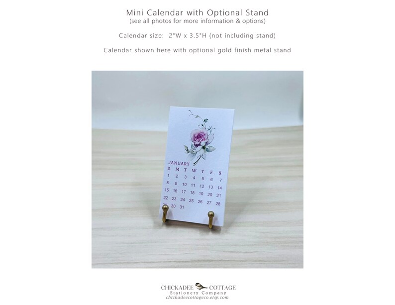 K&ouml;nnte beinhalten: Ein kleiner, wei&szlig;er Kalender mit einem Blumenmuster und dem Monat Januar. Der Kalender steht auf einem goldenen Metallst&auml;nder. Der Kalender ist 5 cm breit und 9 cm hoch.
