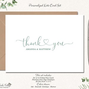 May include: A personalized note card set featuring a white card with the words "thank you" in emerald green script, along with the names "AMANDA & MATTHEW." The set includes 10 folded cards and premium envelopes, A2 size (4.25" x 5.5"). A silver pen rests on the right.