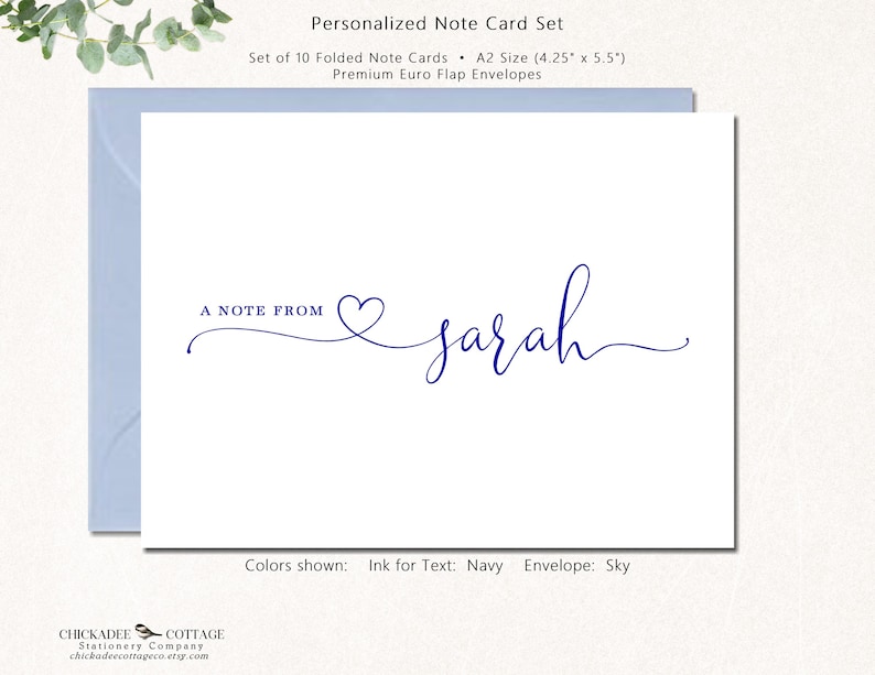 May include: A white note card with navy blue text that reads "A NOTE FROM" followed by the name "sarah" in cursive. The card is inside a light blue envelope. The text color is navy, and the envelope color is sky.