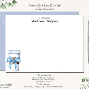May include: Personalized note card set featuring a watercolour illustration of a coffee cup with a blue ribbon. The set includes 10 folded note cards and envelopes. The card size is 10.8 cm by 14 cm. The ink colour is black, the envelope colour is sky blue, and the bow colour is cornflower blue.