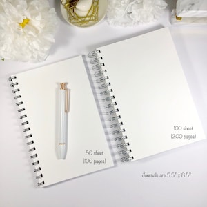 May include: Two white spiral bound journals with silver binding. The smaller journal has 50 sheets (100 pages) and the larger journal has 100 sheets (200 pages). The text "Journals are 5.5" x 8.5" is printed on the larger journal.