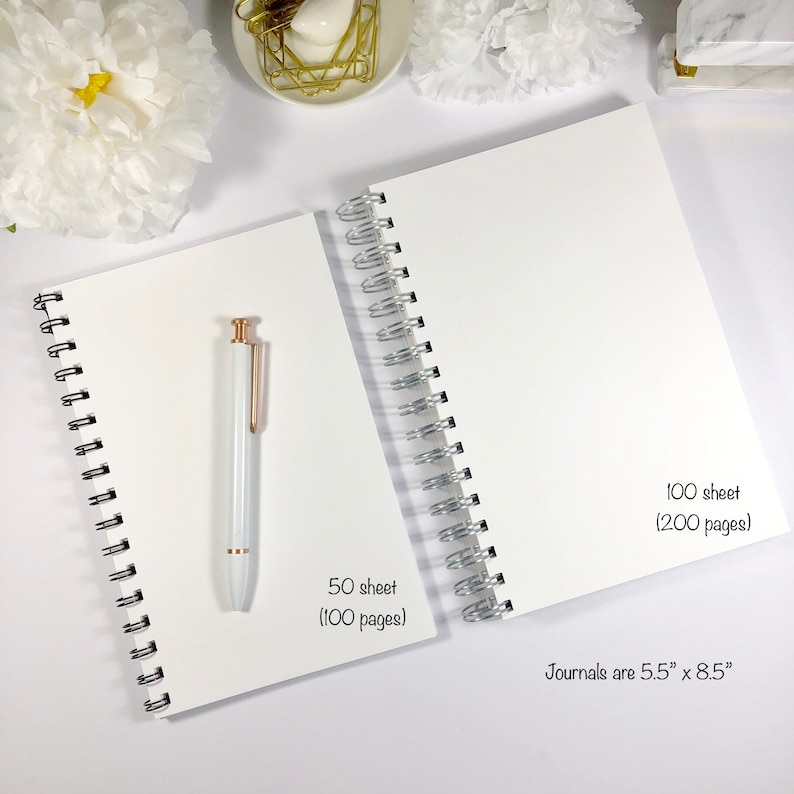 May include: Two white spiral bound journals with silver binding. The smaller journal has 50 sheets (100 pages) and the larger journal has 100 sheets (200 pages). The text "Journals are 5.5" x 8.5" is printed on the larger journal.