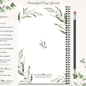 May include: A personalized prayer journal with a black coil binding and a watercolor design of olive branches. The journal is 5.5 inches by 8.5 inches and has 50 or 100 sheets of 80lb text weight paper. The journal is available in a variety of font choices and coil colors.