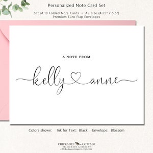May include: A white personalized note card with the names "kelly & anne" in black script, with a heart symbol between the names. The card is inside a pink envelope. The text "A NOTE FROM" is above the names. The set includes 10 folded note cards, each 4.25" x 5.5".