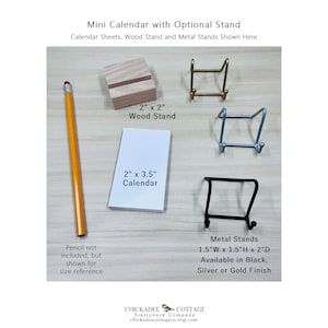 K&ouml;nnte beinhalten: Ein Mini-Kalender mit den Ma&szlig;en 5,1 cm x 8,9 cm, gezeigt mit einem 5,1 cm x 5,1 cm gro&szlig;en Holzst&auml;nder und einem Metallst&auml;nder. Der Metallst&auml;nder ist in Schwarz, Silber oder Gold erh&auml;ltlich. Der Metallst&auml;nder misst 3,8 cm breit, 3,8 cm hoch und 5,1 cm tief.