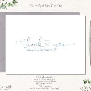 May include: A white note card with the words "thank you" in blue script, personalized with the names "AMANDA & MATTHEW." The card is inside a light gray envelope, with a silver pen to the right. The set includes 10 folded note cards.