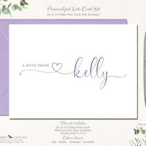 May include: A personalized note card set with lavender envelopes. The white cards feature the text "A NOTE FROM" and a name in purple script. The set includes 10 folded cards, premium envelopes, and is A2 size (4.25" x 5.5"). A silver pen is next to the cards.