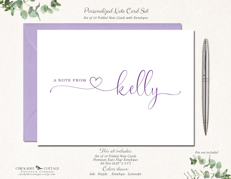 May include: A personalized note card set with lavender envelopes. The white cards feature the text "A NOTE FROM" and a name in purple script. The set includes 10 folded cards, premium envelopes, and is A2 size (4.25" x 5.5"). A silver pen is next to the cards.