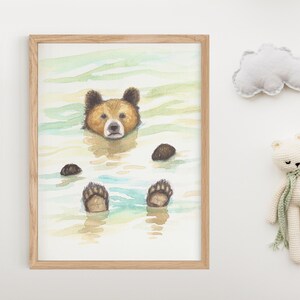 May include: A watercolor painting of a brown bear swimming in a blue and green lake. The bear's paws are visible above the water. The painting is framed in a light wood frame.