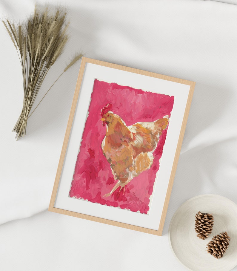 Puede incluir: Una pintura enmarcada de una gallina marr&oacute;n sobre un fondo rosa. La gallina est&aacute; mirando hacia el lado derecho del marco y tiene la cabeza girada hacia la izquierda. La pintura est&aacute; en un marco de madera claro.