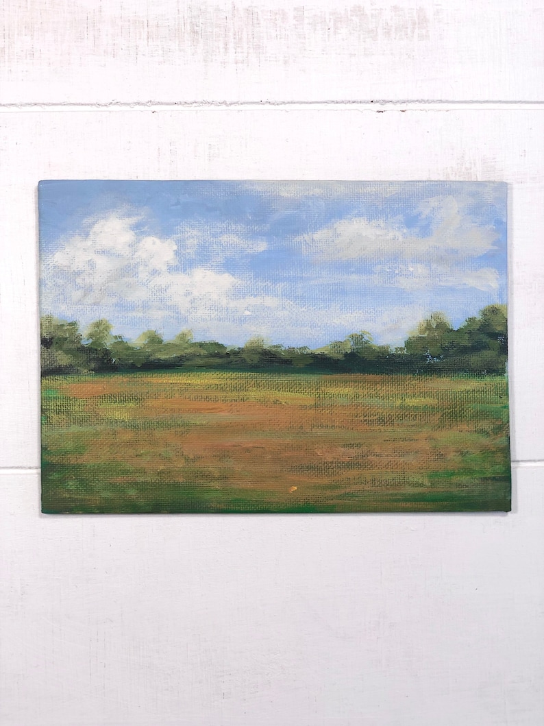 May include: A painting depicting a field with green grass and a brown dirt path. The sky is blue with white clouds.