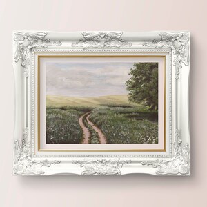 May include: A framed painting of a landscape with a dirt road leading through a field of green grass and white flowers. The sky is a light blue with white clouds. A single tree stands on the right side of the road.