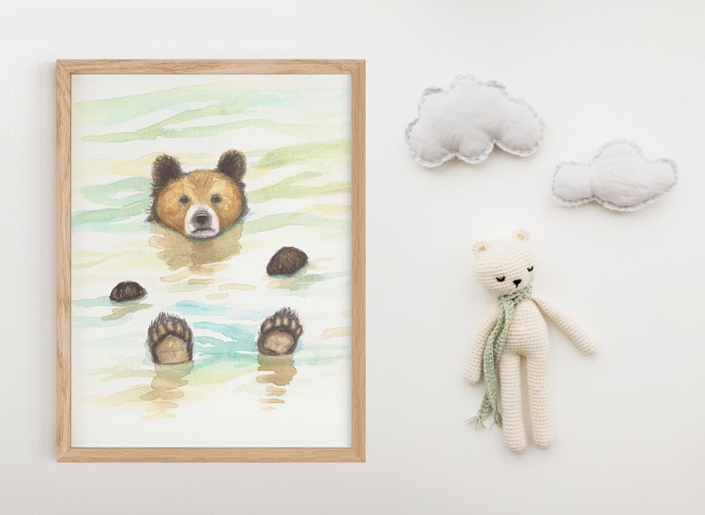 May include: A watercolor painting of a brown bear swimming in a blue and green lake. The bear's paws are visible above the water. The painting is framed in a light wood frame.