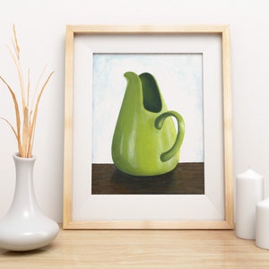May include: A framed painting of a green ceramic pitcher with a rounded body and a curved handle. The pitcher is sitting on a wooden table.