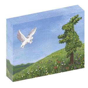 Puede incluir: Un conejo blanco con alas vuela sobre un campo verde de hierba con flores silvestres. Un árbol verde con un tronco marrón se encuentra en el campo.