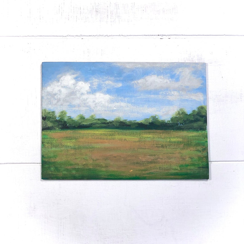 May include: A painting depicting a field with a line of trees in the background. The sky is blue with white clouds. The field is green and brown.