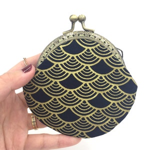 May include: A black coin purse with a gold scale pattern and a brass clasp.