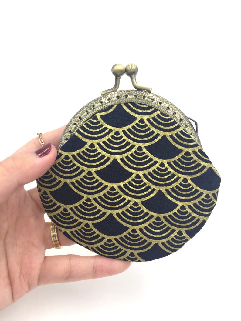 May include: A black coin purse with a gold scale pattern and a brass clasp.
