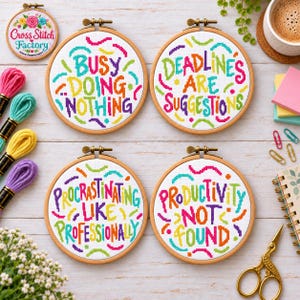 Op de afbeelding: Vier ronde houten borduurringen met kruissteekontwerpen en kleurrijke tekst. De zinnen luiden: BUSY DOING NOTHING, DEADLINES ARE SUGGESTIONS, PROCRASTINATING LIKE PROFESSIONALLY en PRODUCTIVITY NOT FOUND, geaccentueerd door kleine, kleurrijke vormen.