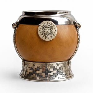 May include: A round mate gourd with a smooth tan surface, featuring a polished silver-colored metal rim and base. The base has an embossed geometric pattern. A circular silver-colored emblem depicting a sun with a face is centered on the front.