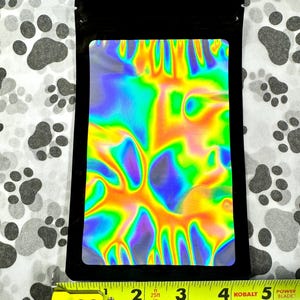 May include: A black resealable pouch with a holographic iridescent rainbow design. The pouch is approximately 4 inches wide and 5 inches tall.