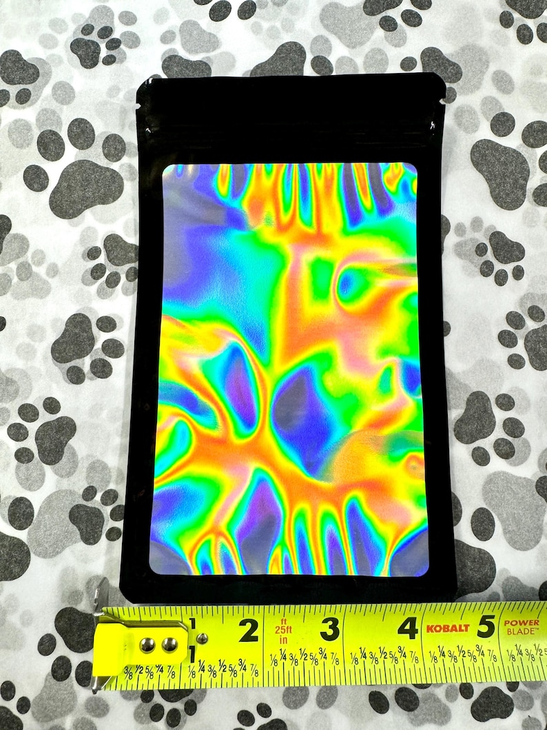 May include: A black resealable pouch with a holographic iridescent rainbow design. The pouch is approximately 4 inches wide and 5 inches tall.