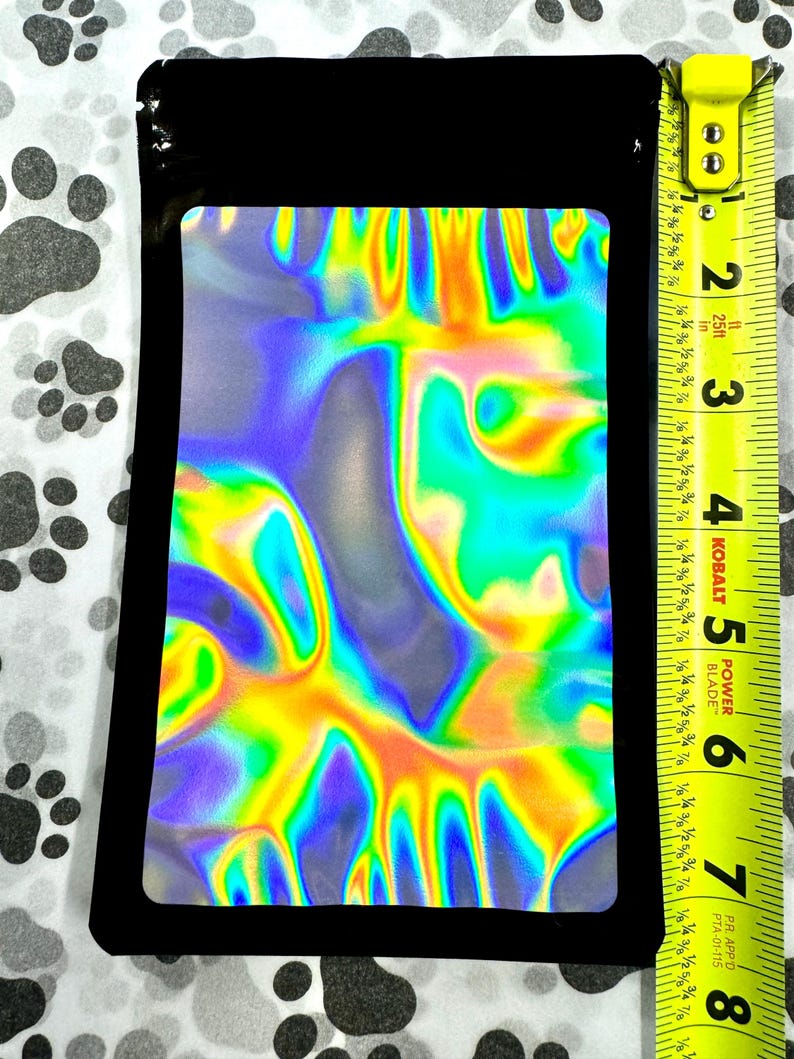 May include: A black zippered pouch with a holographic iridescent inner lining. The pouch is approximately 6 inches tall and 4 inches wide.