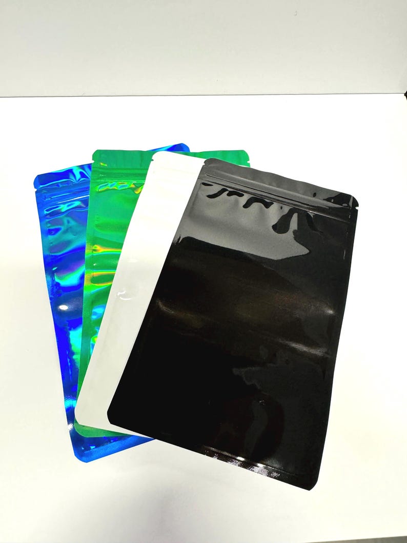 May include: Three stand-up pouches, one iridescent blue, one green, and one black. The pouches are made of a shiny, plastic-like material and have a zipper closure.