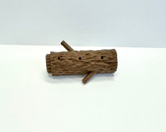 May include: A brown wooden log with three holes drilled into it. The log has two small branches extending out from the sides.