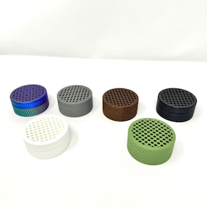 May include: Six small round containers with a patterned design. The containers are in various colors, including white, green, gray, brown, and purple.