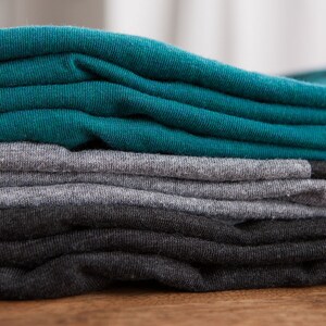 May include: A stack of folded t-shirts in teal, gray, and black.