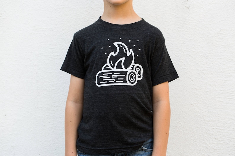 May include: A dark grey t-shirt with a white graphic of a campfire with flames and logs.