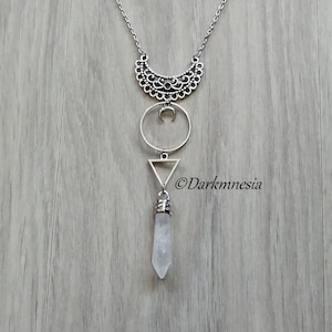 Peut inclure: Un collier en argent avec un pendentif en forme de croissant de lune, un pendentif triangulaire géométrique et une pointe de cristal de quartz clair.