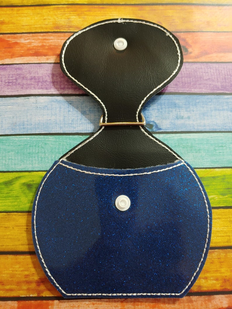 Może przedstawiać: Niebieska błyszcząca portmonetka na monety z czarną g&oacute;rą z imitacji sk&oacute;ry i białym zatrzaskiem. Portmonetka ma biały obszyty brzeg.