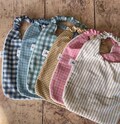 Floral elasticated bib for babies and children, made of double gauze Oeko-Tex certified fabric. Ideal for nursery and canteen use; easy to put on, soft and absorbent. product logo