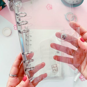 May include: Clear plastic binder with a silver ring mechanism and a snap closure. The binder has a small logo that says "HAM" in a stylized font.