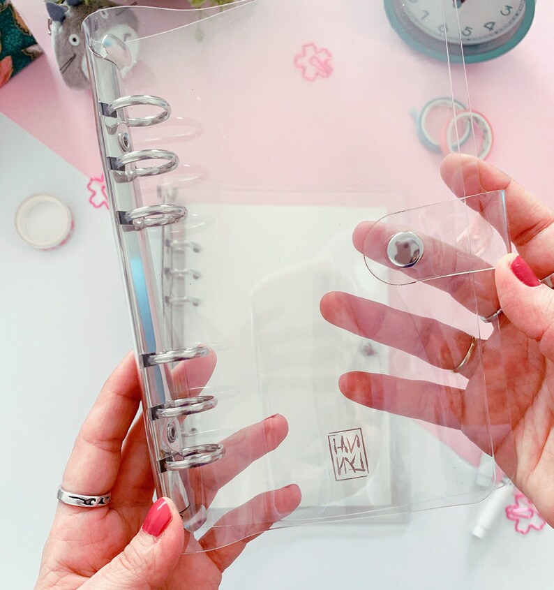 May include: Clear plastic binder with a silver ring mechanism and a snap closure. The binder has a small logo that says "HAM" in a stylized font.