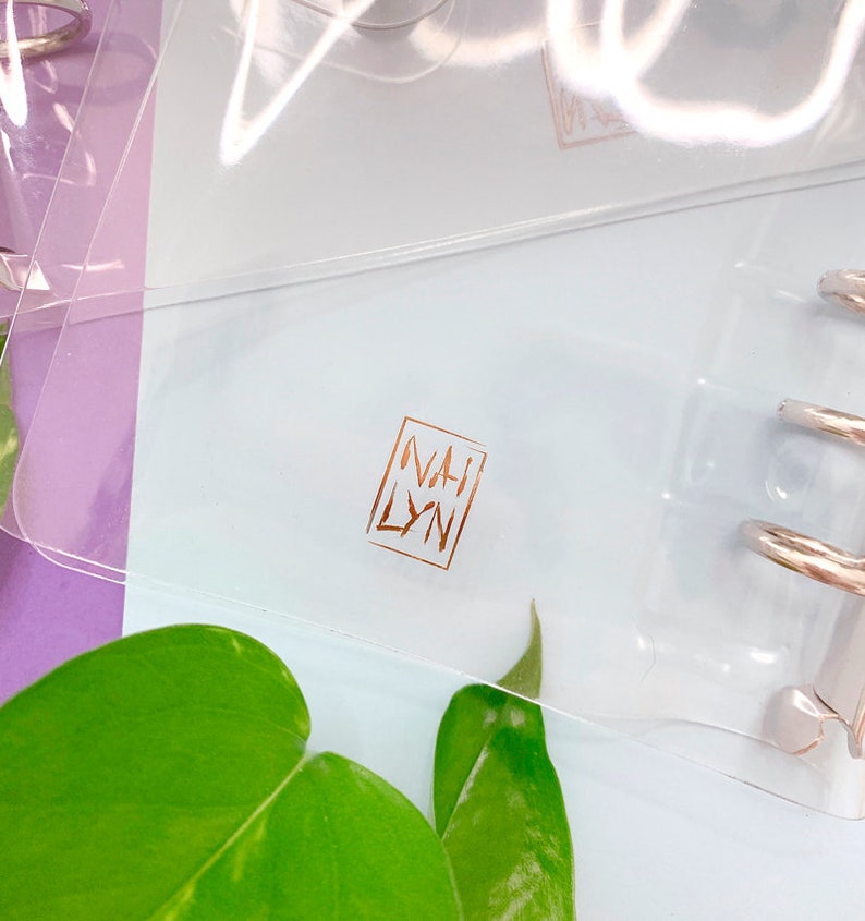 May include: A clear plastic binder with a gold foil logo that says "NAH LYN" on the front.