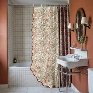 May include: A floral patterned shower curtain with a scalloped edge in a bathroom setting. The curtain features a cream background with pink and green floral designs. A matching patterned curtain is visible to the right.
