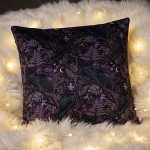 May include: A square throw pillow featuring a dark purple and black pattern of ravens perched on tree branches amidst ferns and small crescent moons. The fabric displays a dense, repeating botanical and avian motif in deep violet and black tones.