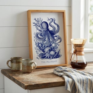 May include: A framed blue and white octopus print with the text "THE PELHAMS" sits on a wooden surface. Two ceramic mugs and a glass coffee maker are also on the surface. A blue and white striped cloth is draped nearby.