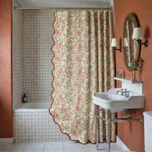 May include: A patterned shower curtain with a scalloped edge in a bathroom. The curtain has a cream background with pink and green floral designs. The bathroom includes a white sink, mirror, and a bathtub.