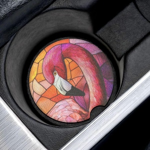 May include: A pink flamingo with stained glass-like patterns in shades of pink, orange, and yellow. The flamingo is in a car cup holder.