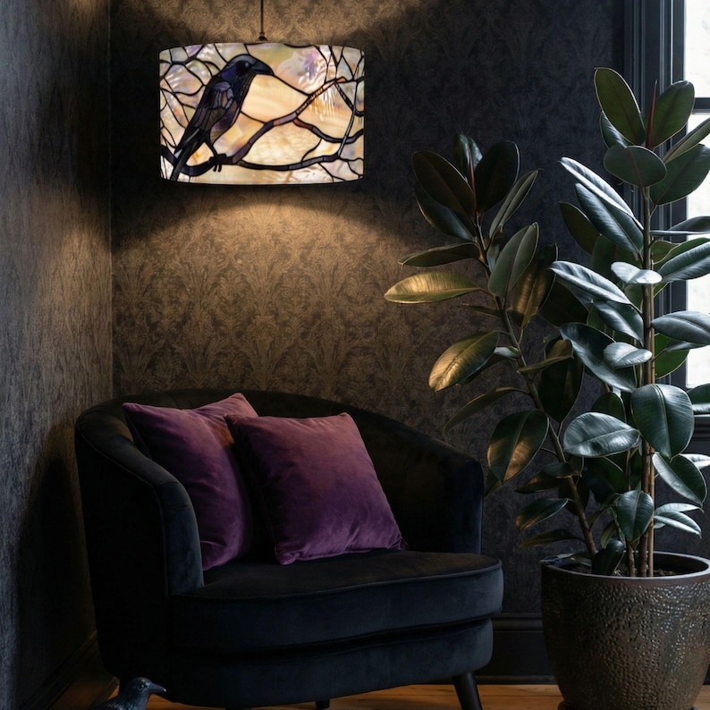May include: A cylindrical stained glass pendant lamp featuring a black crow perched on dark branches against a cream and iridescent background. The lamp emits a warm glow, illuminating the surrounding area with a soft, diffused light pattern.