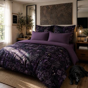 May include: A bedding set featuring a dark purple and black duvet cover and matching pillowcases with a detailed botanical and celestial print including crescent moons, ferns, and flowers. The set includes solid purple accent pillows.