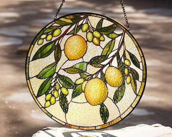 May include: A round stained glass window hanging from a chain. The window features a lemon tree with green leaves and yellow lemons.
