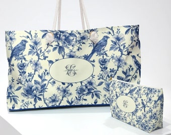 May include: A white tote bag with blue floral and bird designs. The bag has a blue trim and a matching blue and white cosmetic bag.